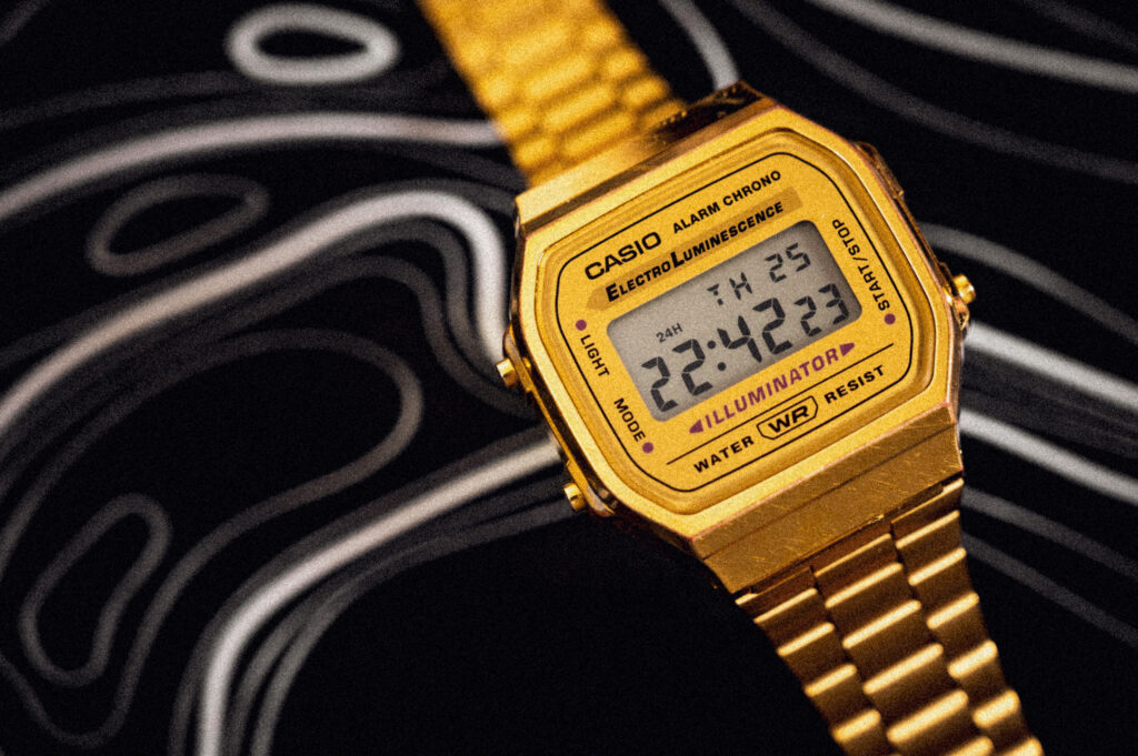 Close-up van een Casio 3298 A168-horloge, rechts uitgelijnd. De achtergrond bestaat uit witte kriegels op zwarte stof.