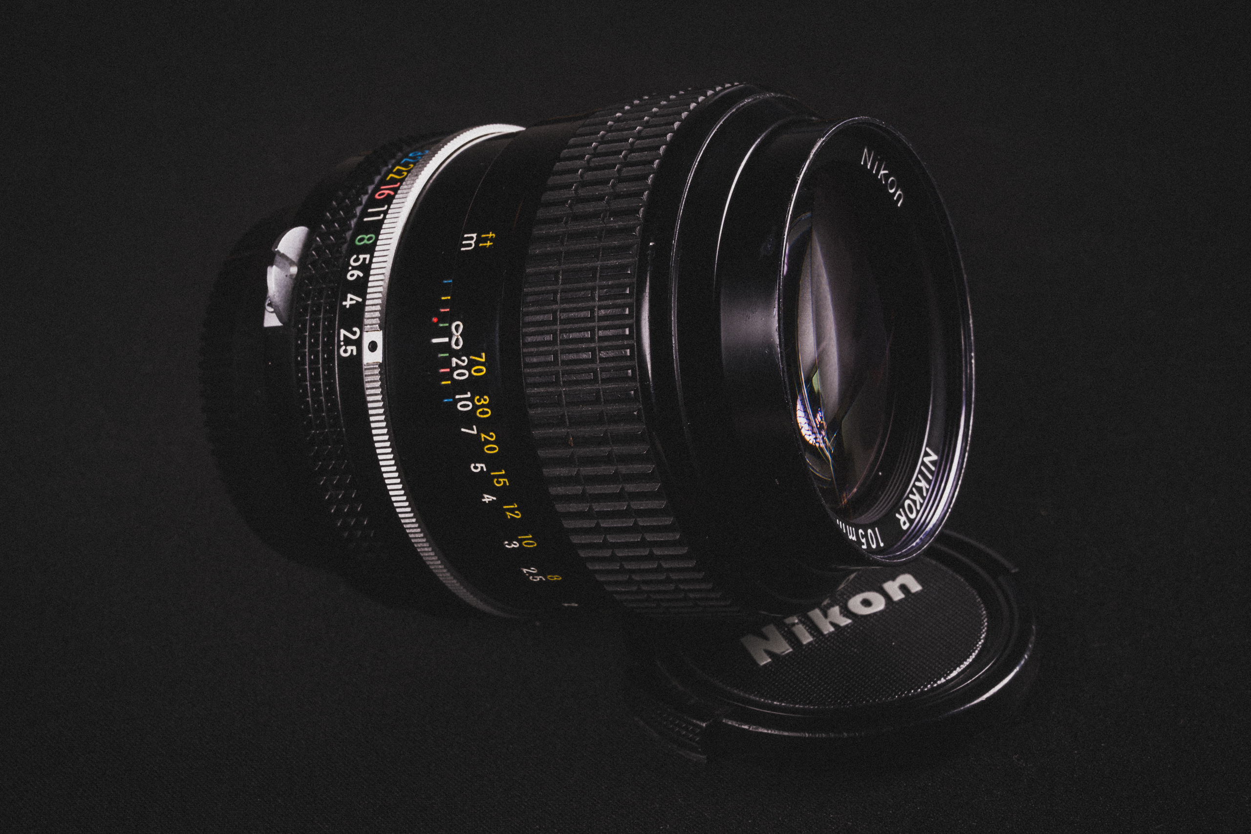 Nikkot 105mm f/2.5 K-lens, half op de eigen lensdop gelegd.